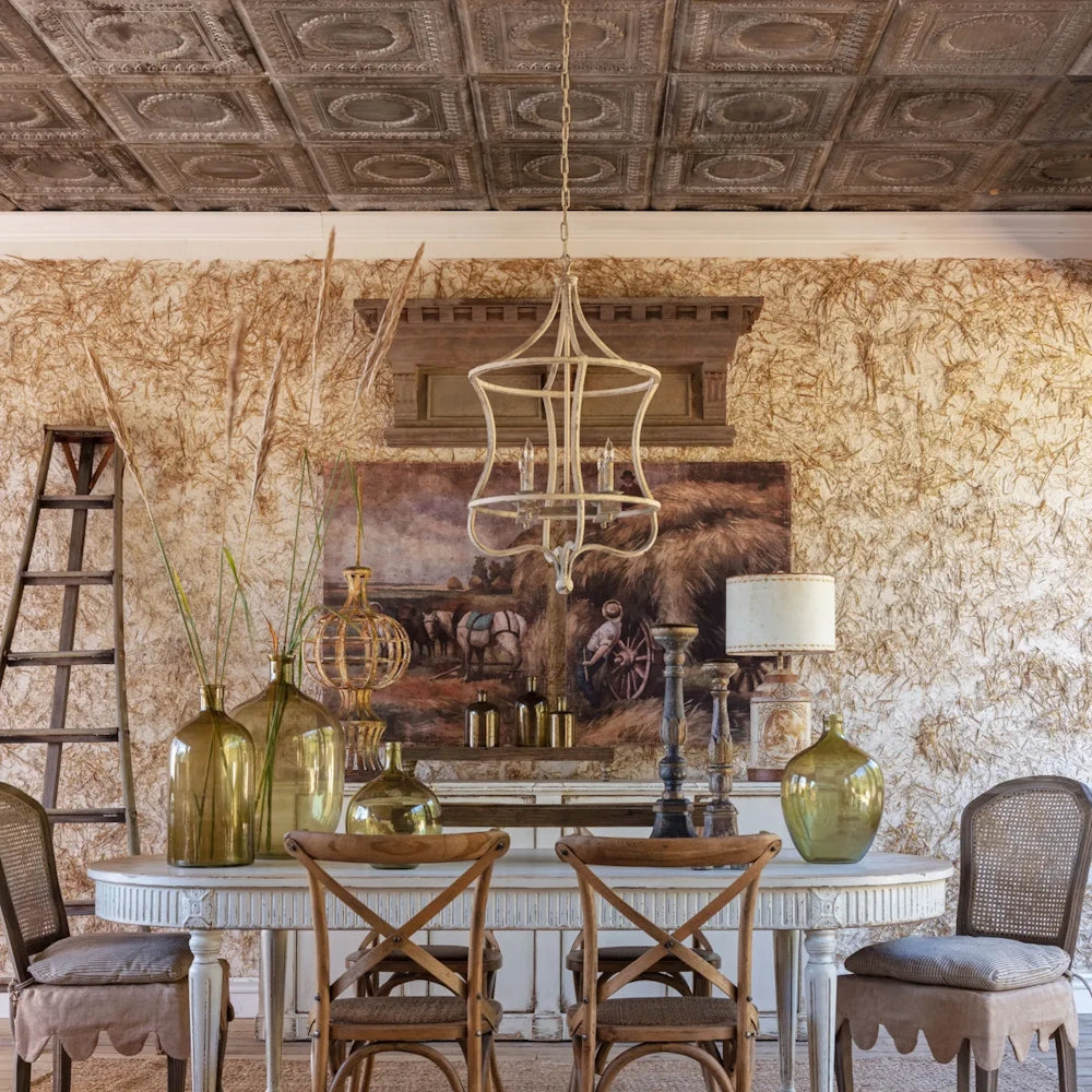 A rustic dining room with an ornate cage chandelier hanging over a white table with glass vases.