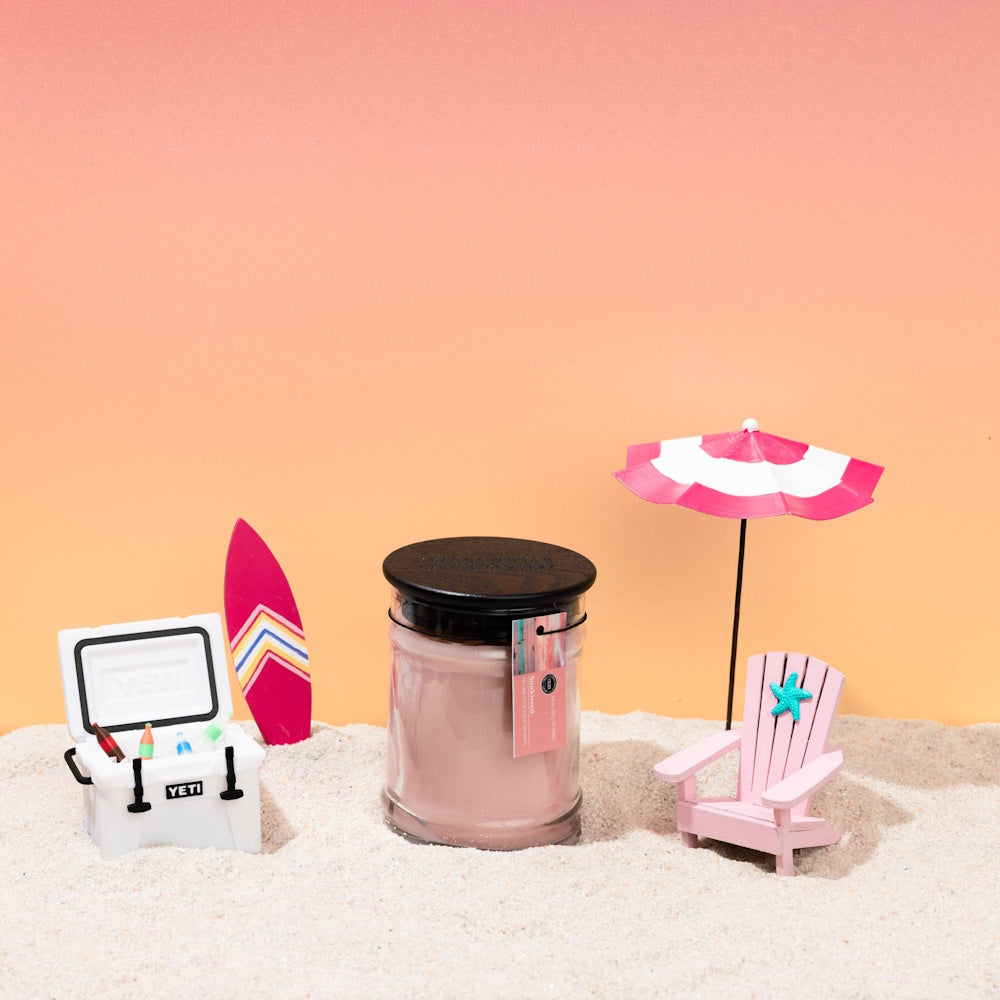 Bridgewater Candle Company Sunkissed jar candle in a miniature beach scene with a tiny Yeti cooler and pink chair.