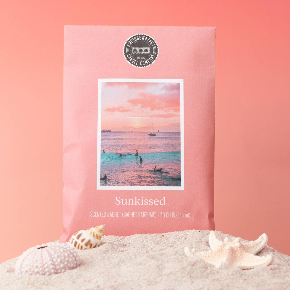 Bridgewater Candle Company Sunkissed scented sachet on beach sand with seashells and starfish.
