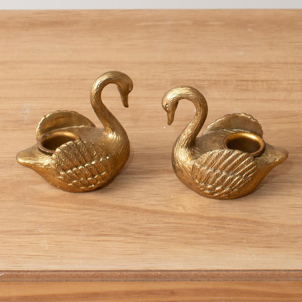 Pair of vintage brass swan tapered candle holders on a light wood surface, perfect for elegant home decor and tablescapes.