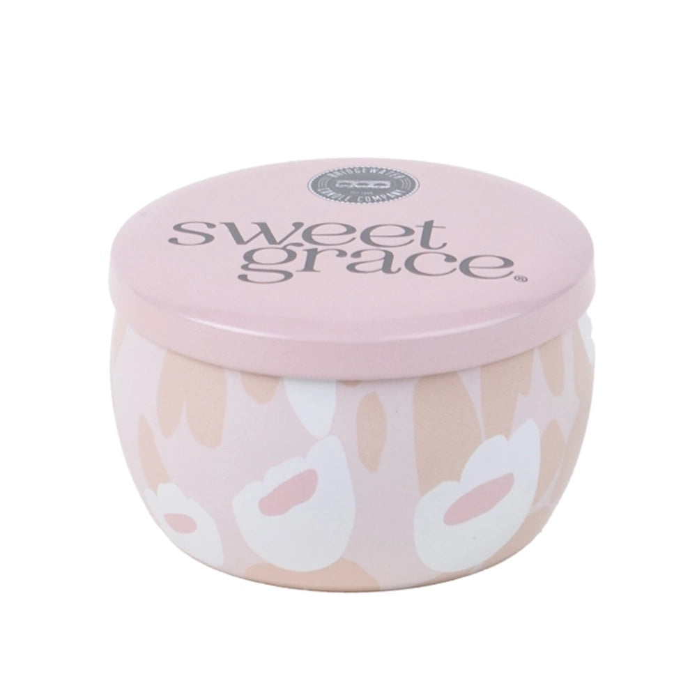 Small round pink candle tin with Sweet Grace logo and floral pattern against a plain background.