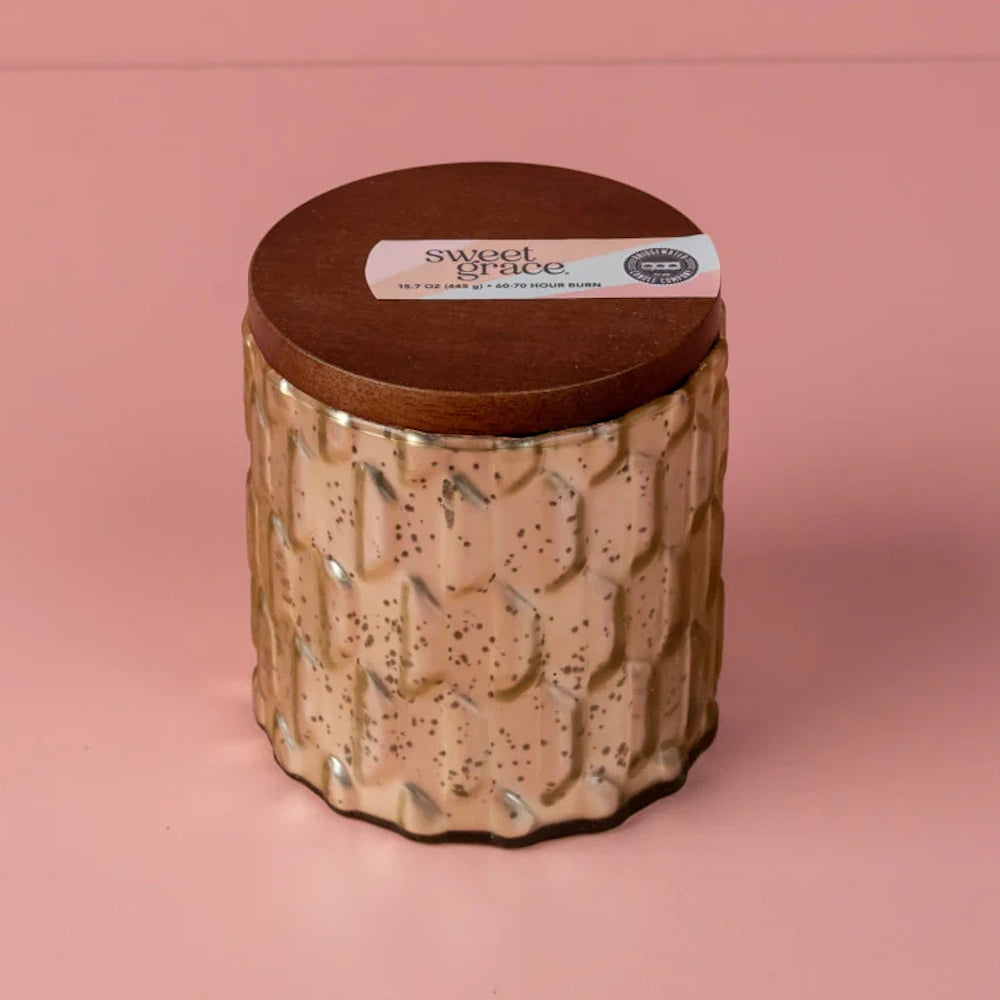 A decorative mercury glass candle jar with a dark wood lid featuring a "Sweet Grace" label on a pink background.
