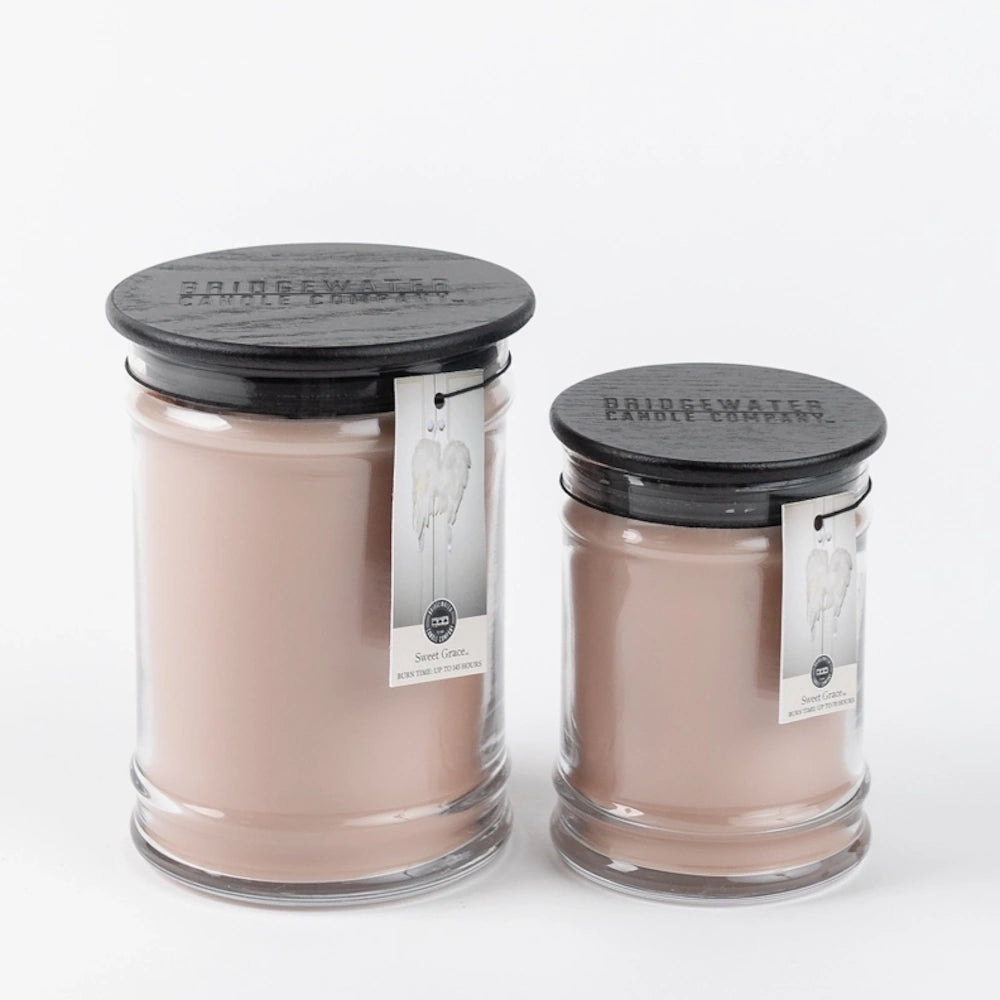 Two glass jar candles filled with beige wax, featuring dark wooden lids and hanging tags.
