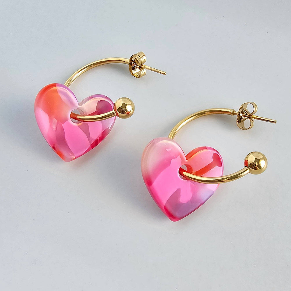 Pair of gold hoop earrings with translucent pink resin heart charms, "Sweetheart Hoops" in Tickled Pink style.