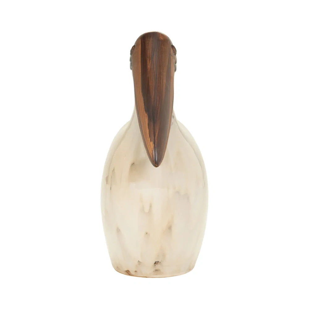 Front view of a tall, marbled beige pelican sculpture with a long brown beak on a white background.