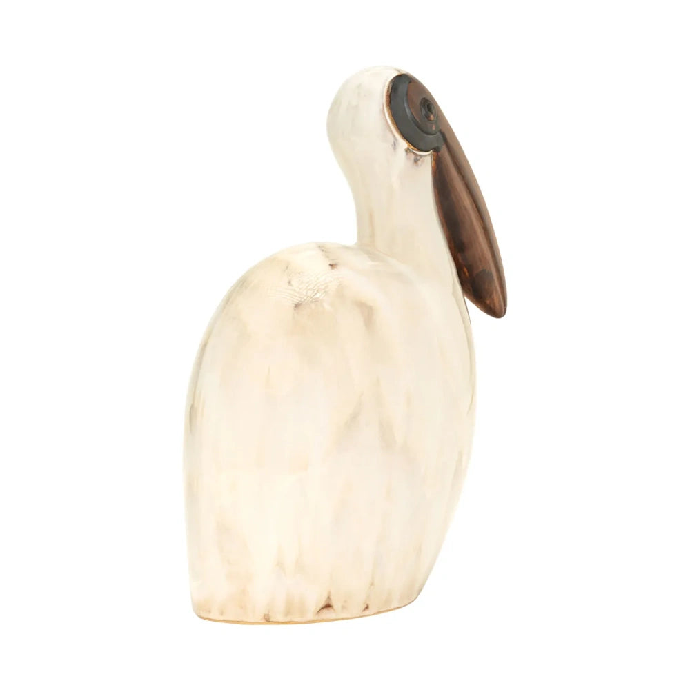 Side profile of a tall pelican sculpture with a cream resin body and dark wood beak, isolated on white.