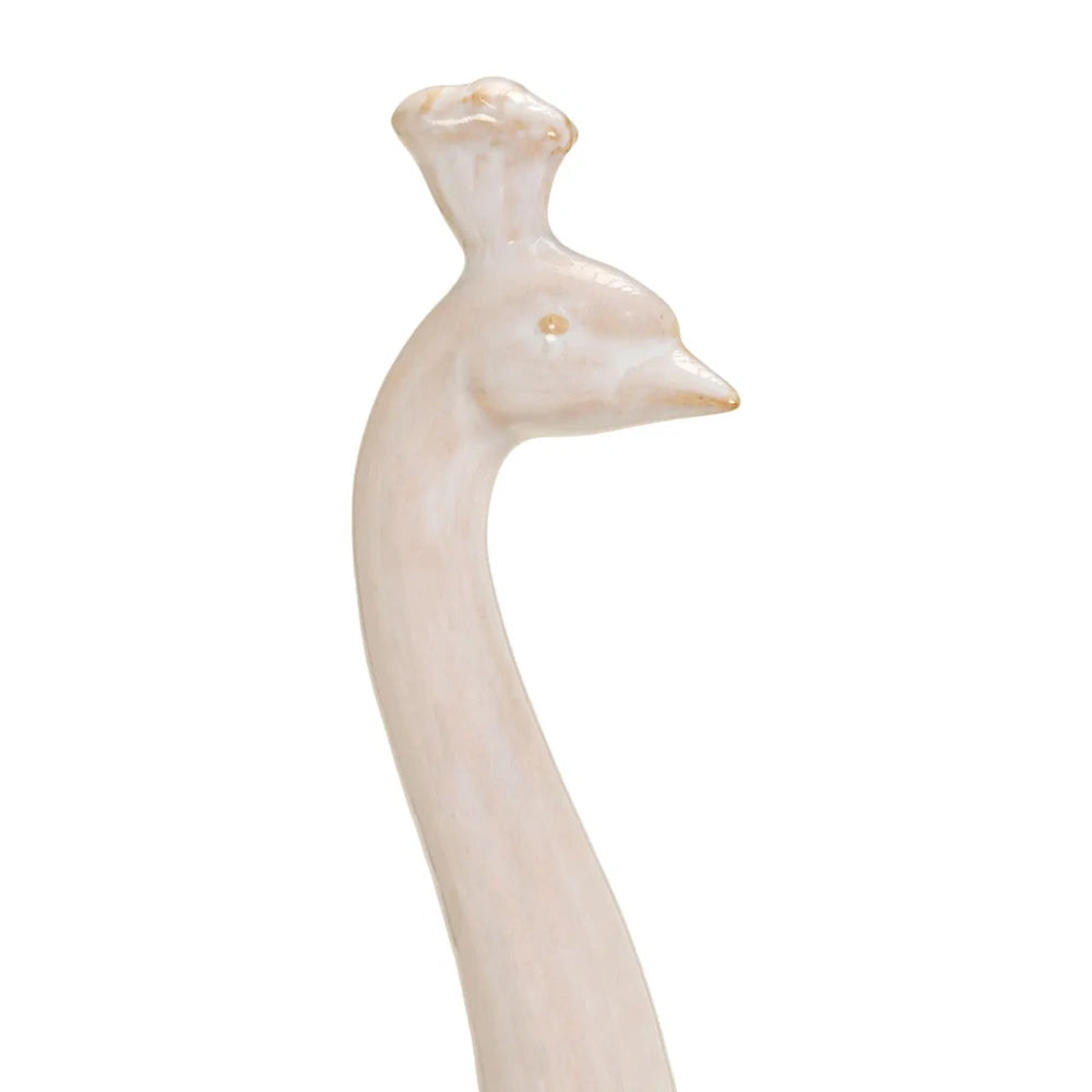 Close-up of the head and sleek neck of a cream-colored peacock sculpture, highlighting its crown crest.