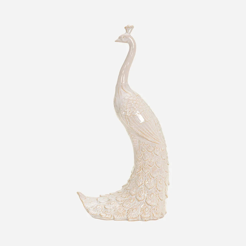 Side profile of a tall, glossy off-white ceramic peacock sculpture with intricate feather detailing.