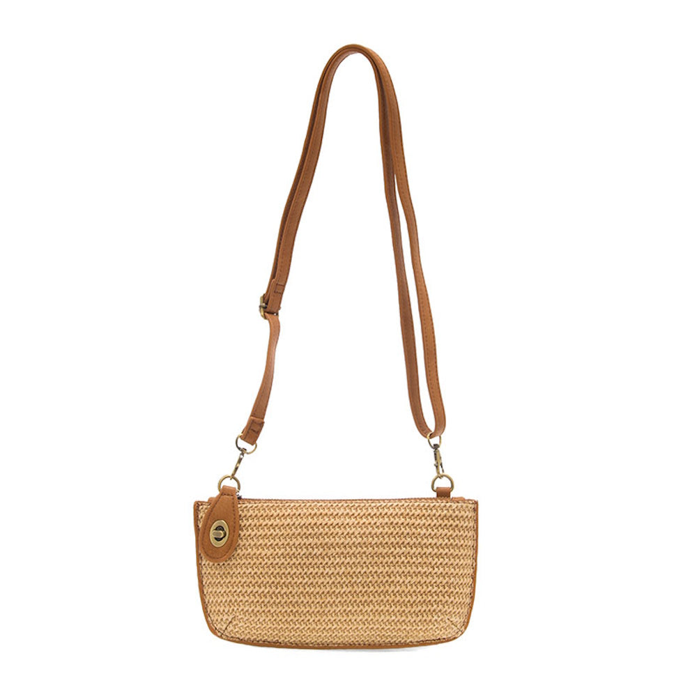 Tan woven straw crossbody bag with a brown faux-leather adjustable strap and gold-tone hardware on a white background.