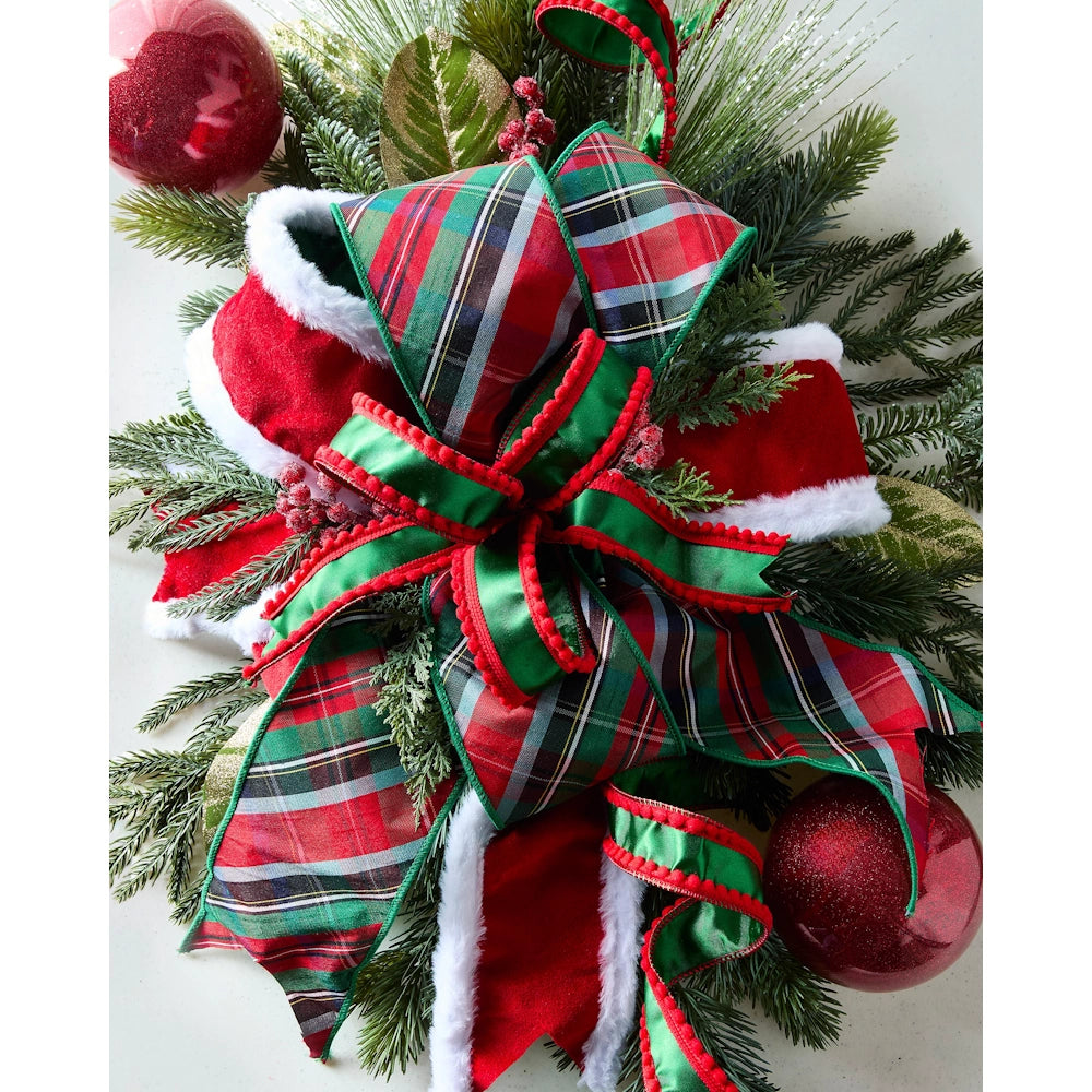 Top-down view of a red and green plaid fabric Christmas ribbon fashioned into a festive holiday bow.