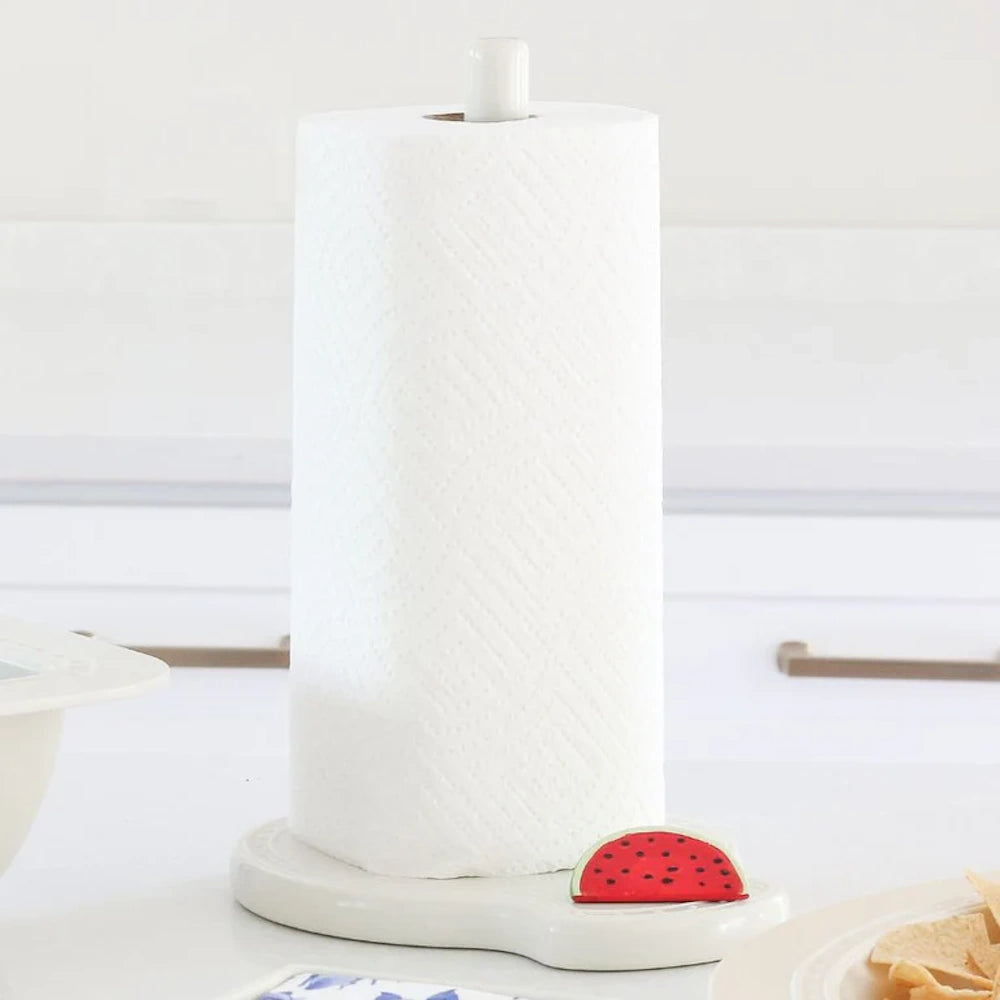 A roll of paper towels on a white ceramic holder featuring a small watermelon slice detail.
