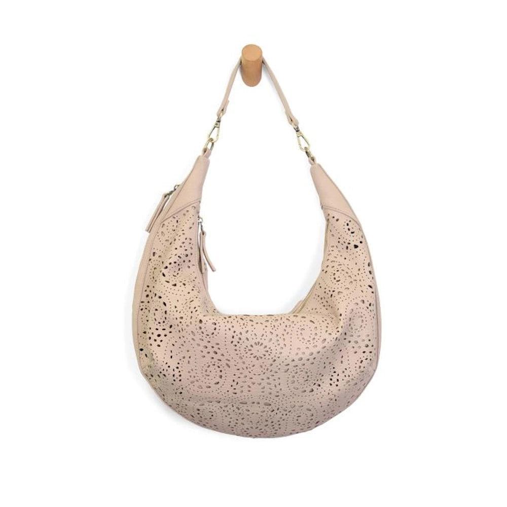 Taupe laser-cut eyelet rhea slouchy crescent bag with top handle hanging on a wooden peg.