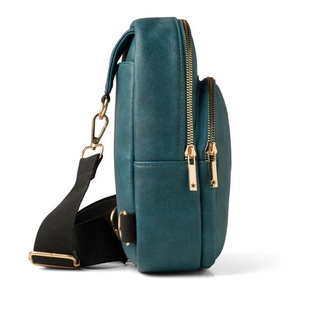 Side view of a teal leather sling bag with gold zippers and a black adjustable strap.