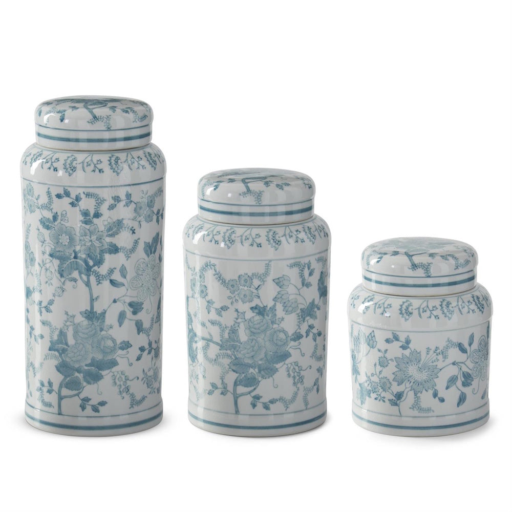 Set of three teal and white floral chinoiserie porcelain lidded jars in varying sizes on a plain white background.