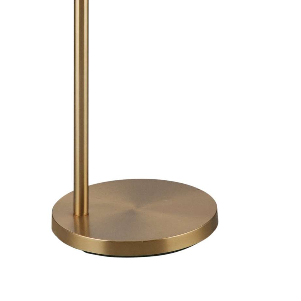 Close-up view of a circular, brushed-brass metal base and slim vertical stand of a modern floor lamp.