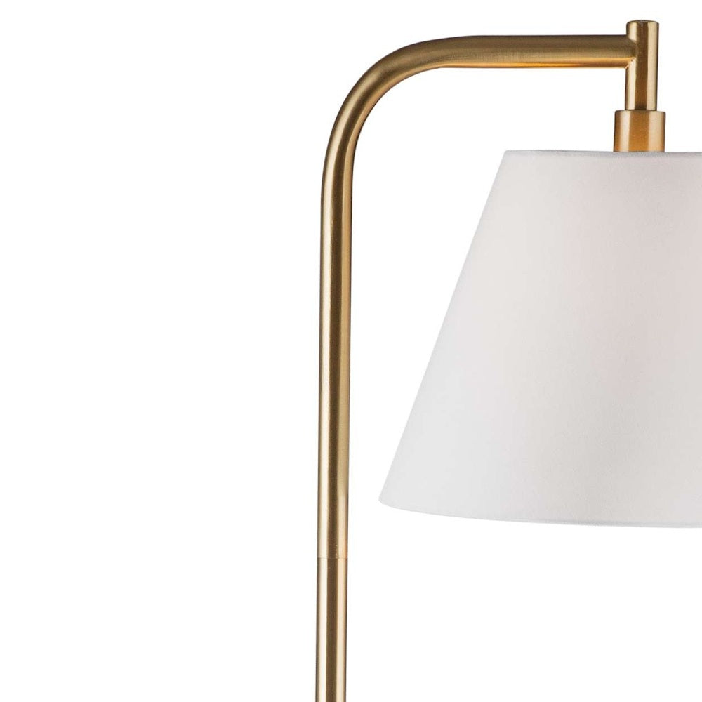 Close-up view of a brushed-brass curved arm holding a white tapered shade on a floor lamp.