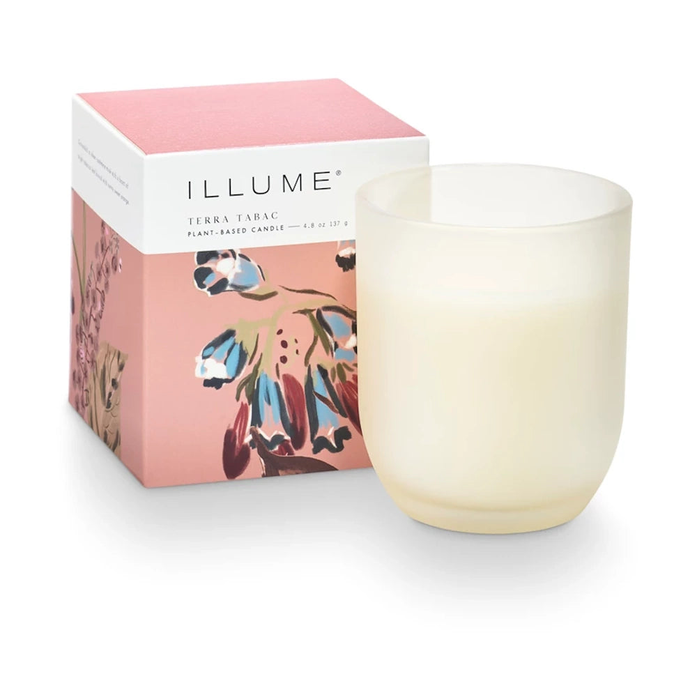 Illume Terra Tabac plant-based candle in a frosted white glass jar next to its pink floral decorative box.
