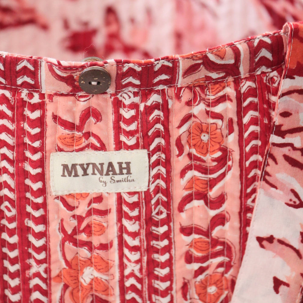 Close-up of a Mynah by Smitha terracotta floral print reversible tote bag featuring a wooden button and quilted fabric.