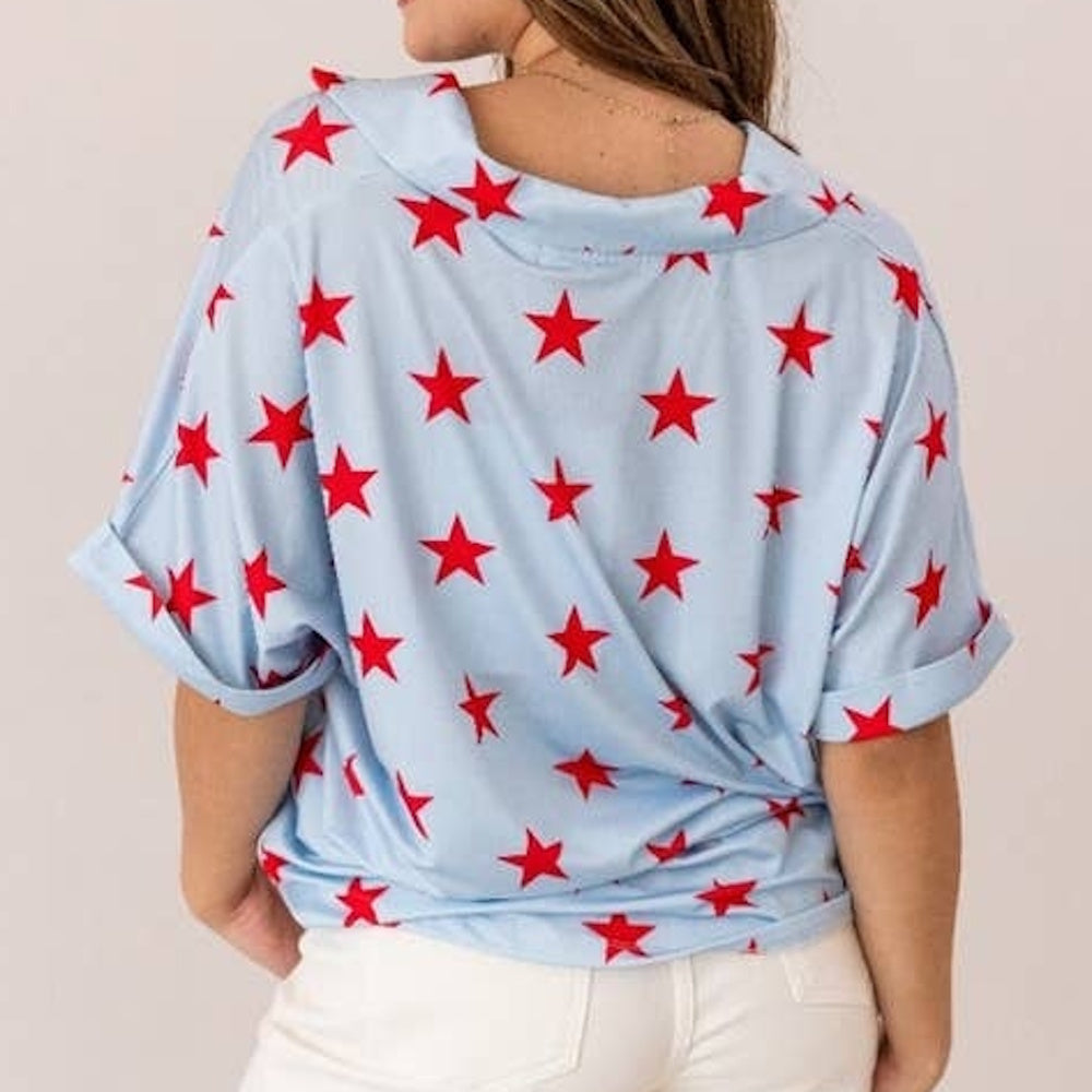 Back view of a woman wearing a light blue short-sleeved shirt with a bright red star pattern.
