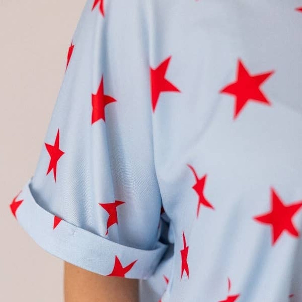 A close-up of a light blue short-sleeved shirt featuring a pattern of bright red stars.