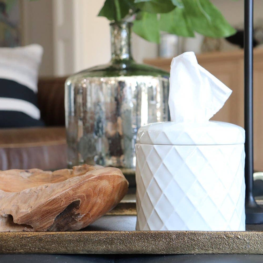 A white, diamond-textured tissue box cover sits on a tray next to a wooden bowl and a glass vase.