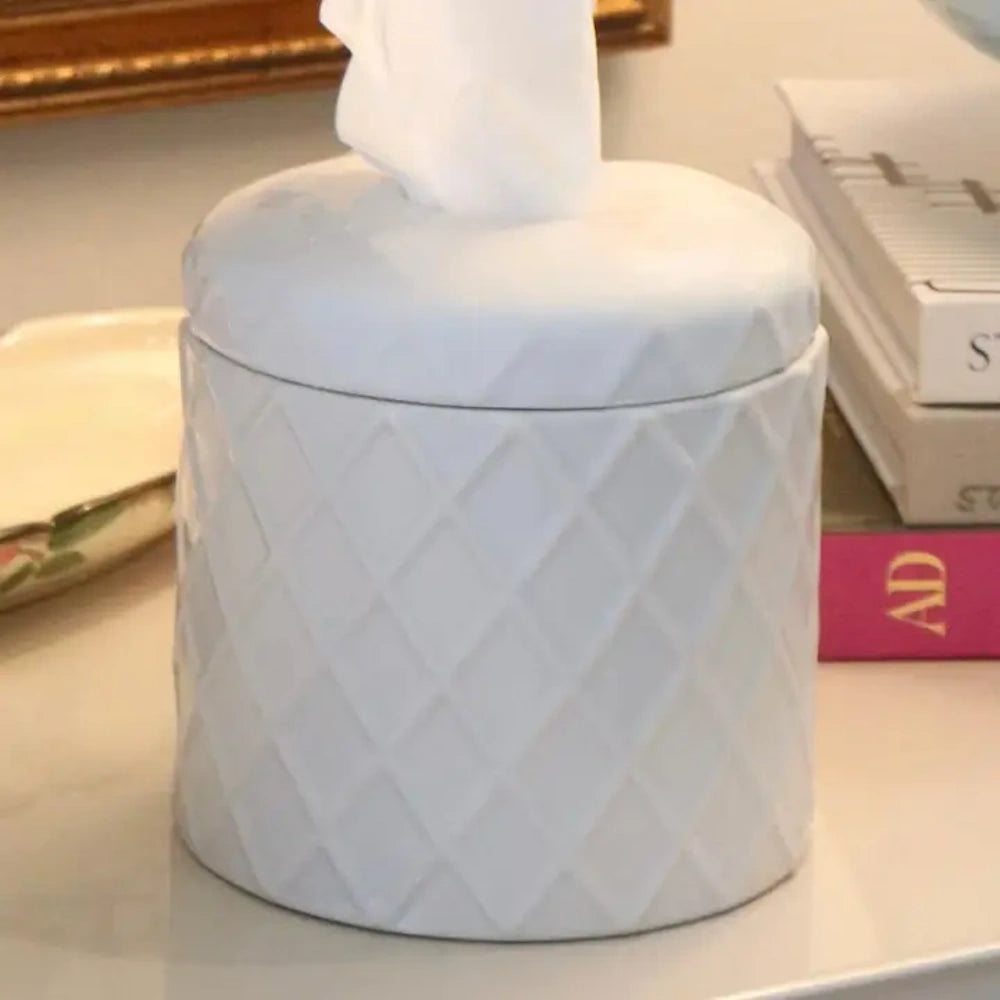 White ceramic cylindrical tissue box cover with a raised diamond pattern and a single tissue popping out.
