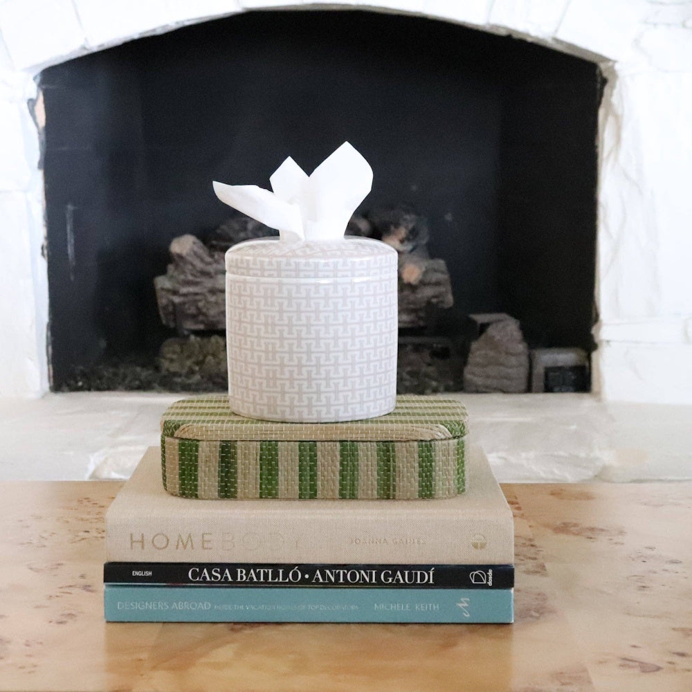 Geometric-patterned tissue vessel on stacked books in front of a fireplace.