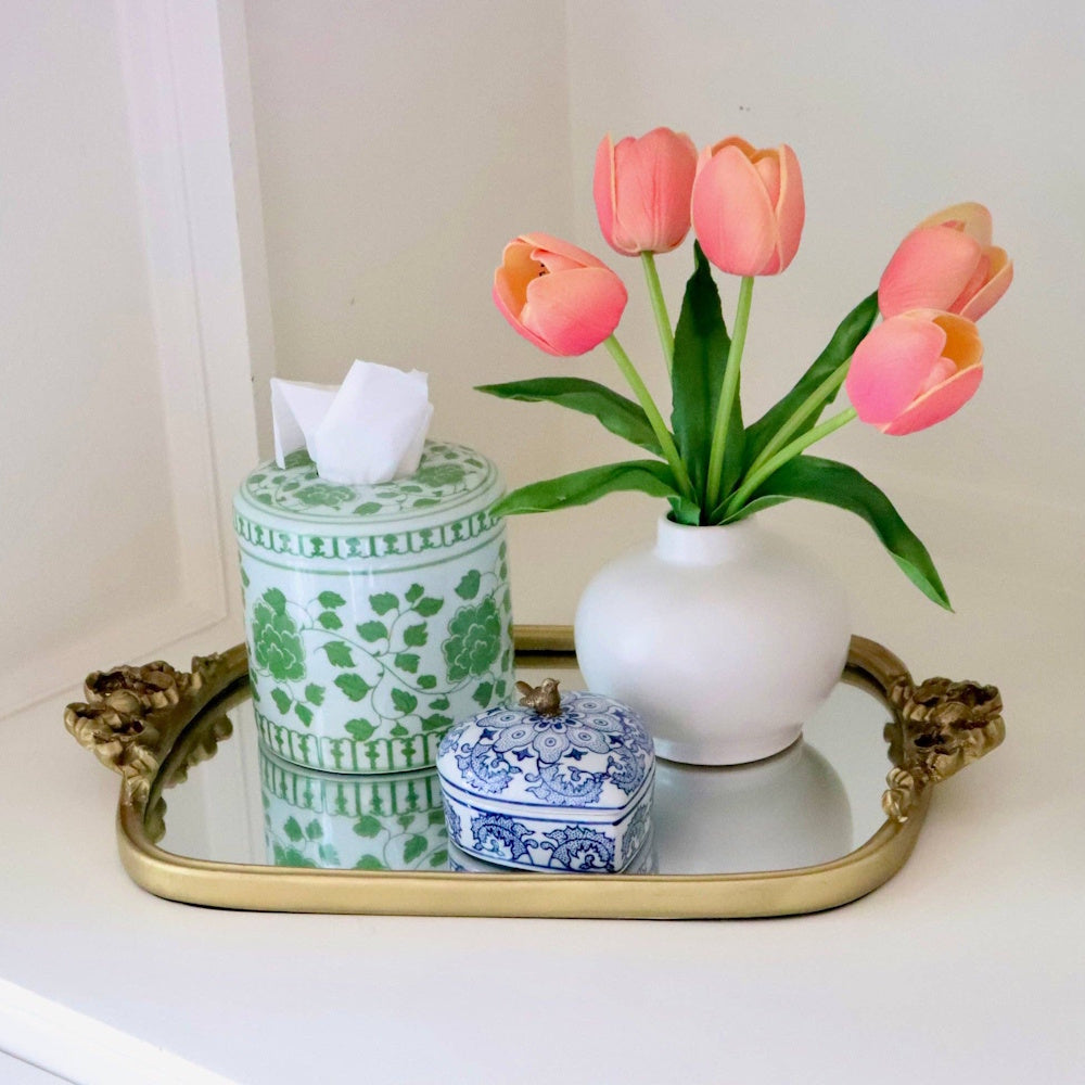 Green and white floral tissue vessel, small trinket box, and tulip vase on a mirrored tray.