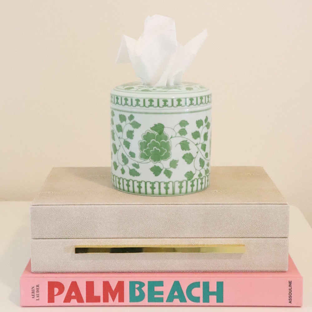 Green and white floral tissue vessel on a decorative box and book.