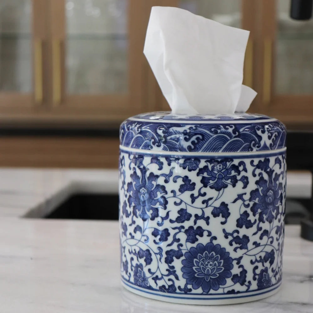 Blue and white floral ceramic tissue canister with a wave pattern lid on a white marble countertop.
