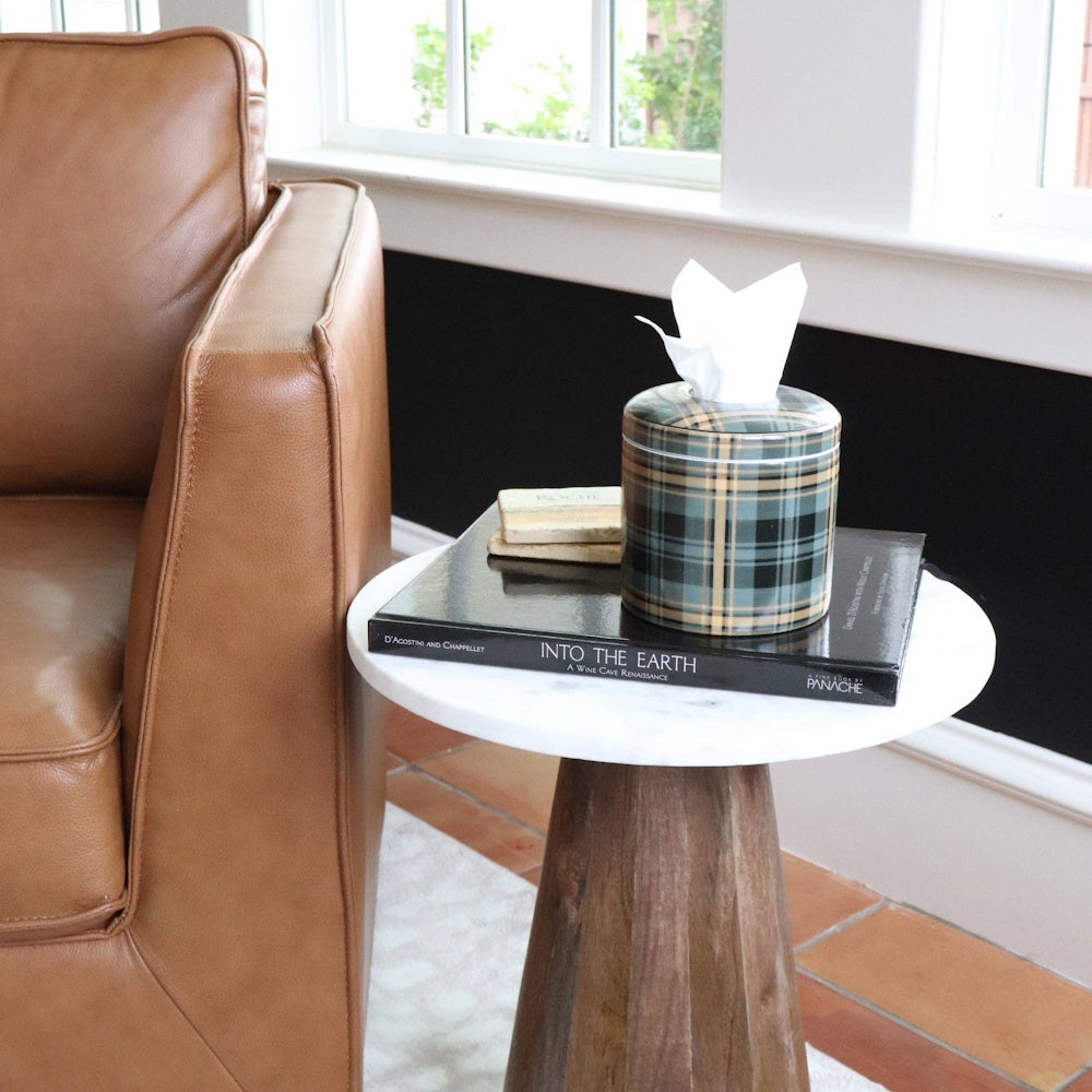 Plaid tissue box cover on a marble side table next to a leather chair in a bright room.
