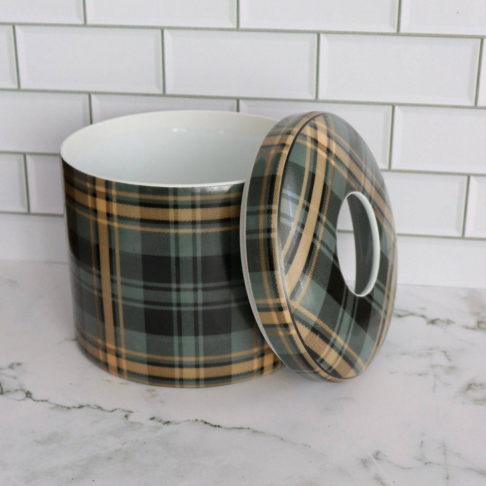 A cylindrical ceramic jar and matching lid with a green and tan plaid pattern on a marble countertop.