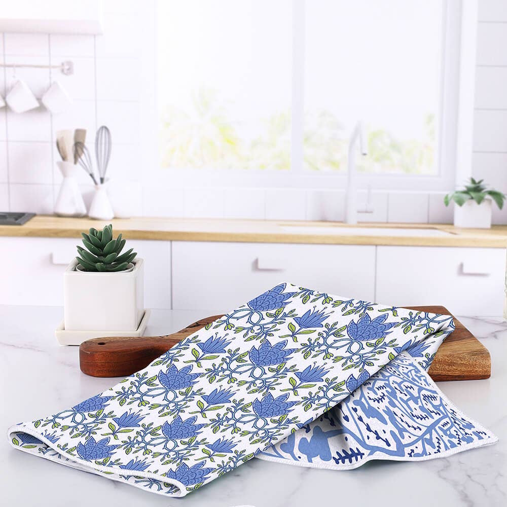 Blue and white floral tea towel draped over a wooden cutting board on a kitchen counter.