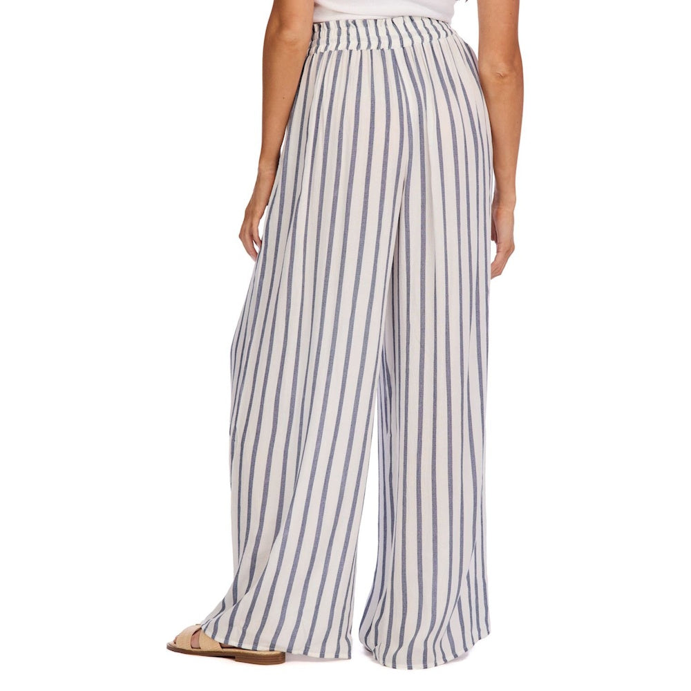 Rear view of a person wearing blue and white striped, wide-leg beach pants with a smocked waistband.