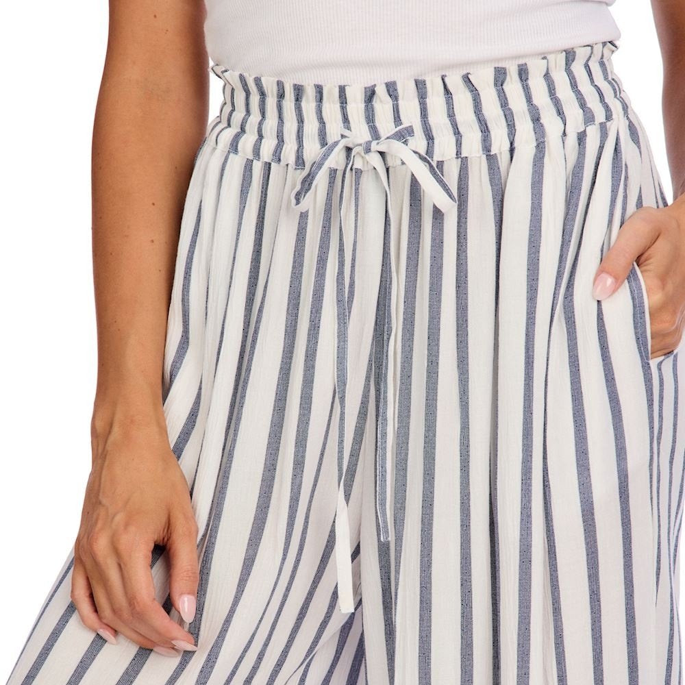 Close-up of a person wearing blue and white striped beach pants with a smocked drawstring waist and side pockets.