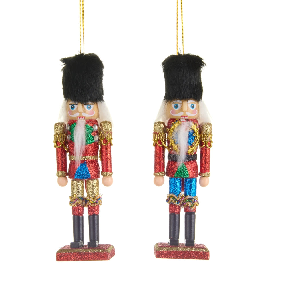 Two glittering nutcracker Christmas tree ornaments hanging side by side, wearing tall black hats and red jackets.