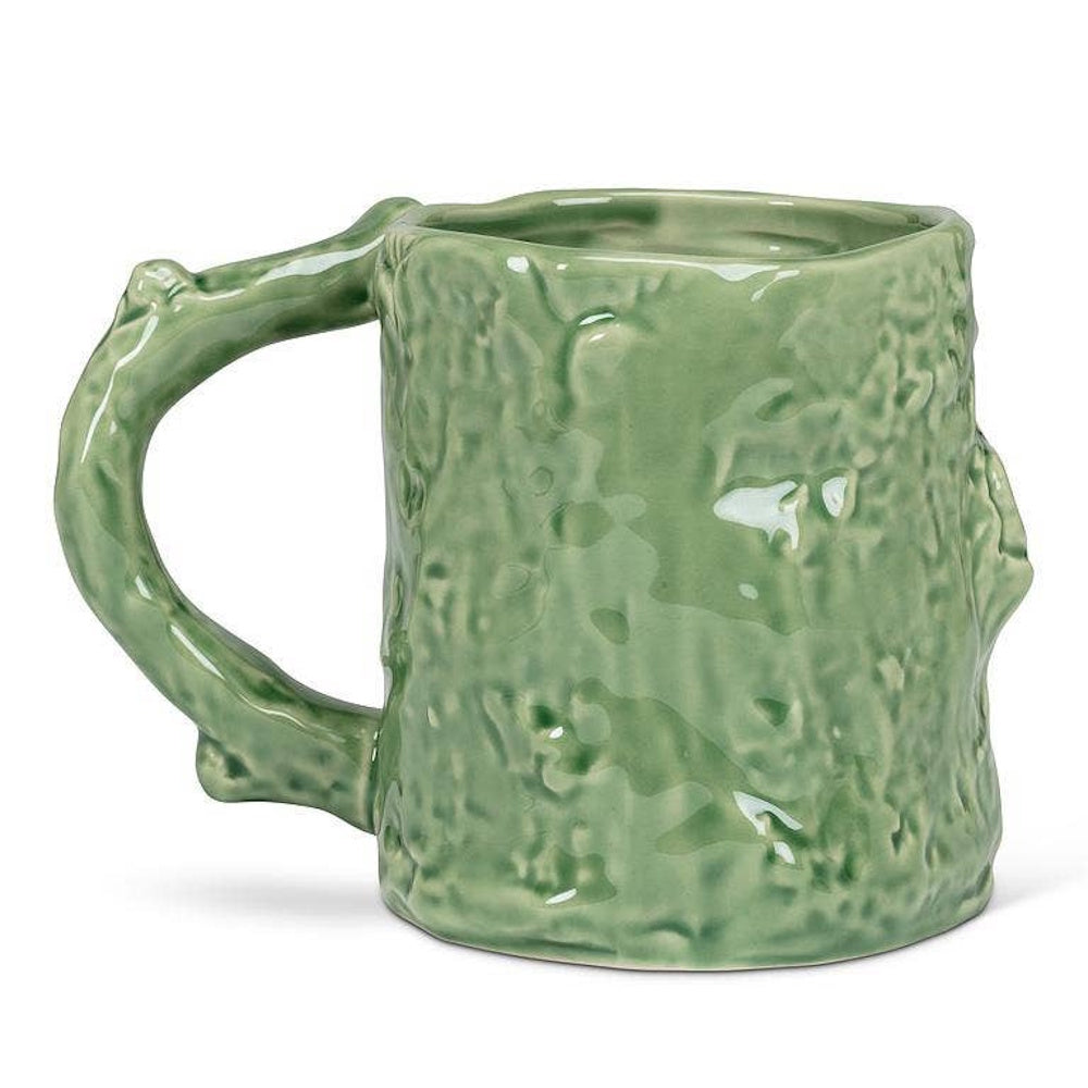 Green ceramic mug shaped like a textured tree trunk with a branch handle on a white background.