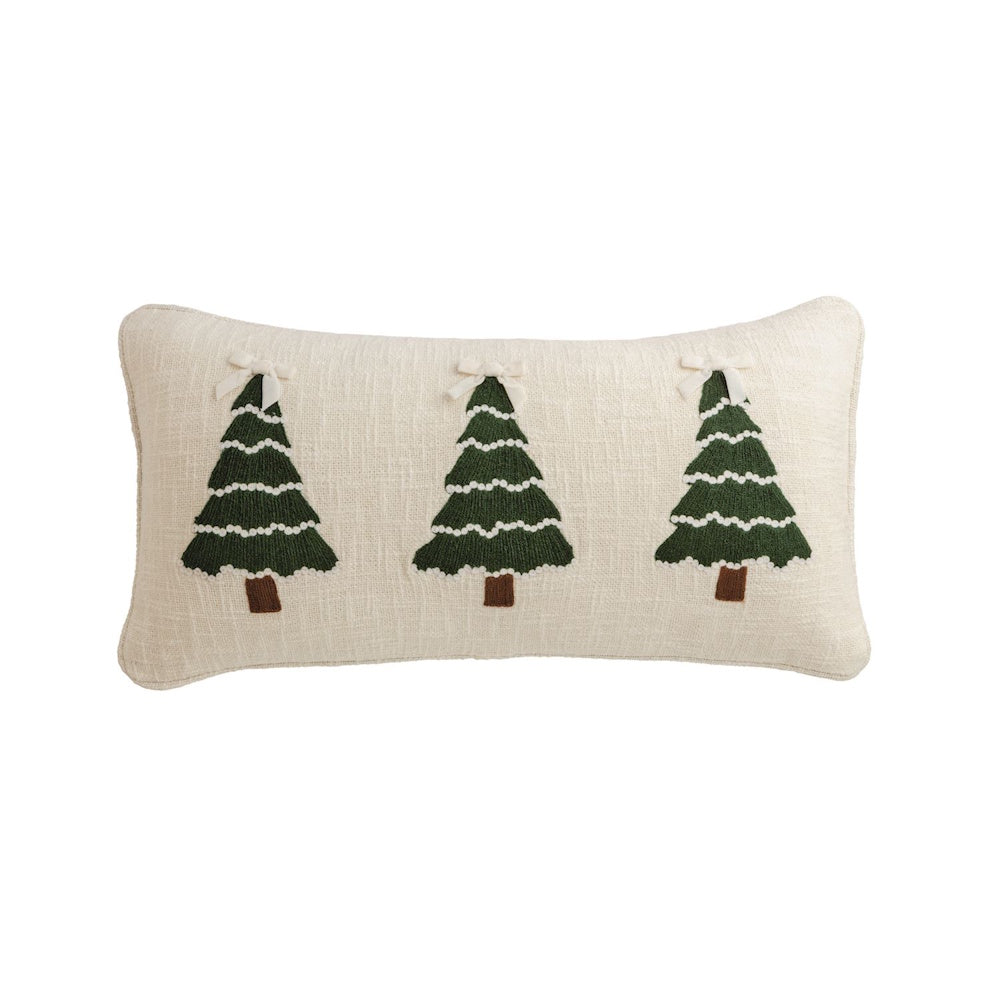 Cream lumbal pillow with embroidered green Christmas trees topped with bows.