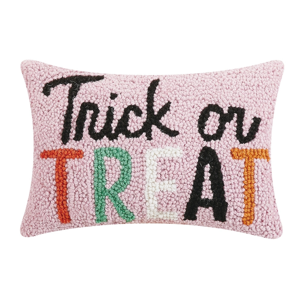 Pink hooked throw pillow featuring "Trick or Treat" in black cursive and multicolored block letters.