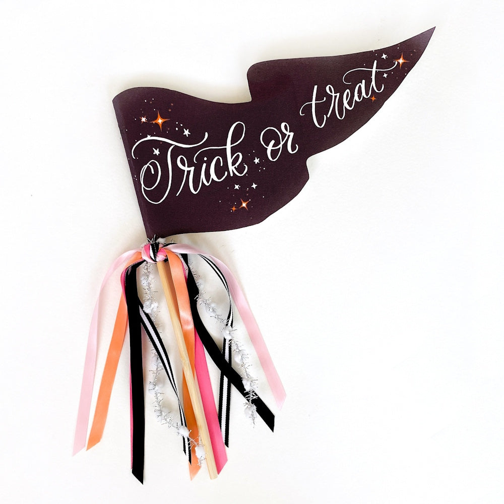 Black Halloween pennant flag reading "Trick or treat" in script, with festive hanging ribbons.