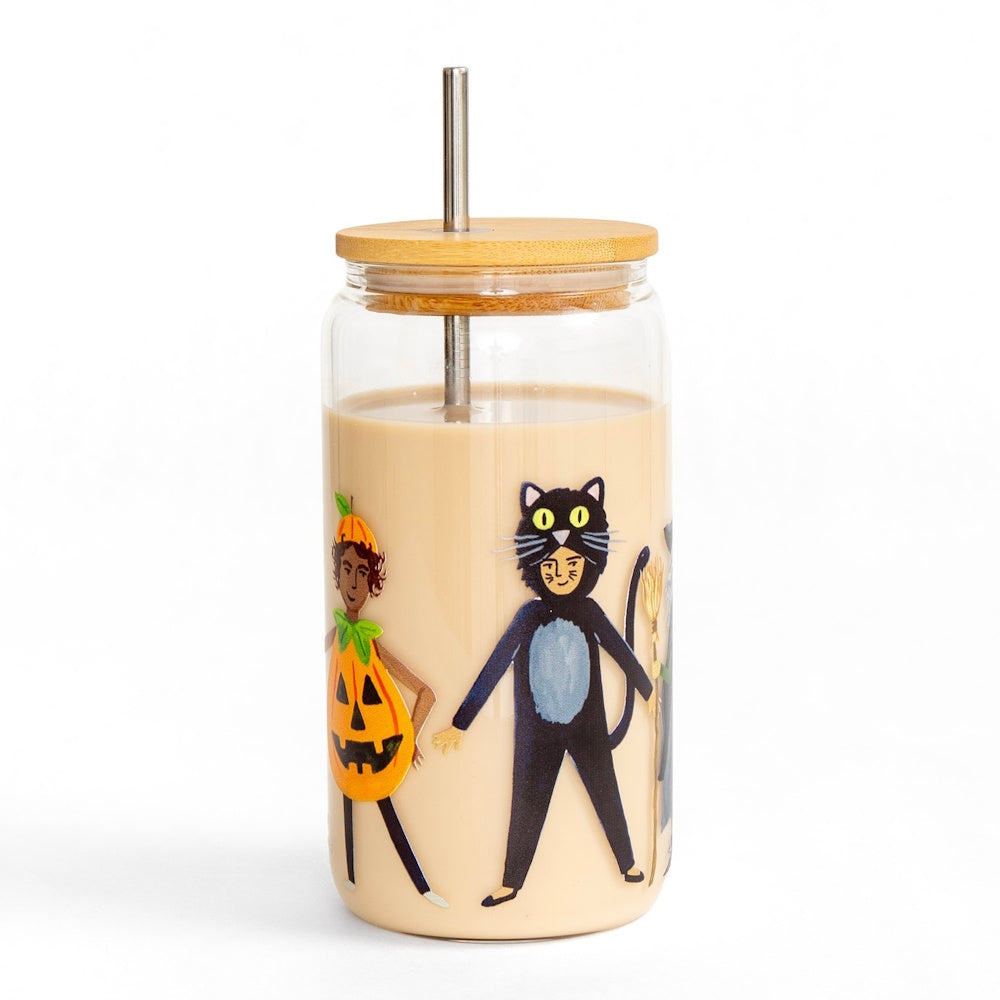 A glass can tumbler filled with iced coffee, decorated with trick-or-treaters, a bamboo lid, and straw.