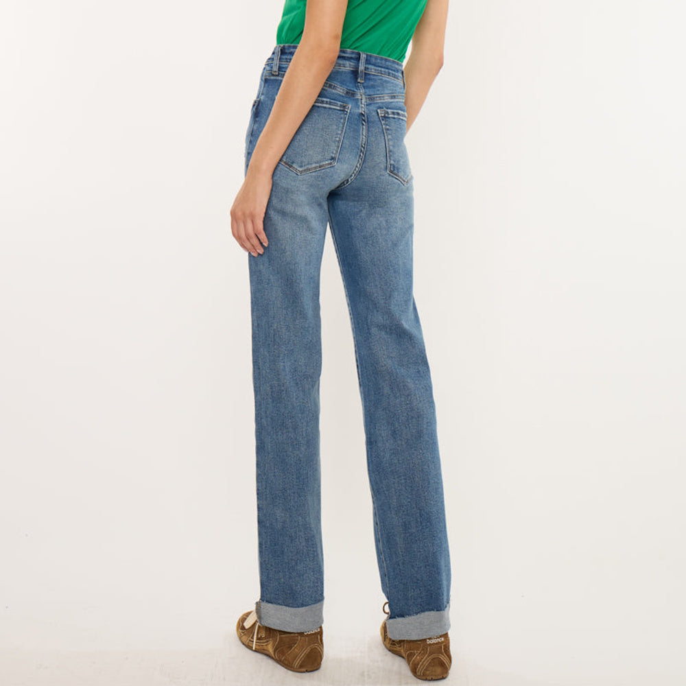 Rear side view of a model wearing high-waisted, straight-leg medium-wash blue jeans with cuffed hems.