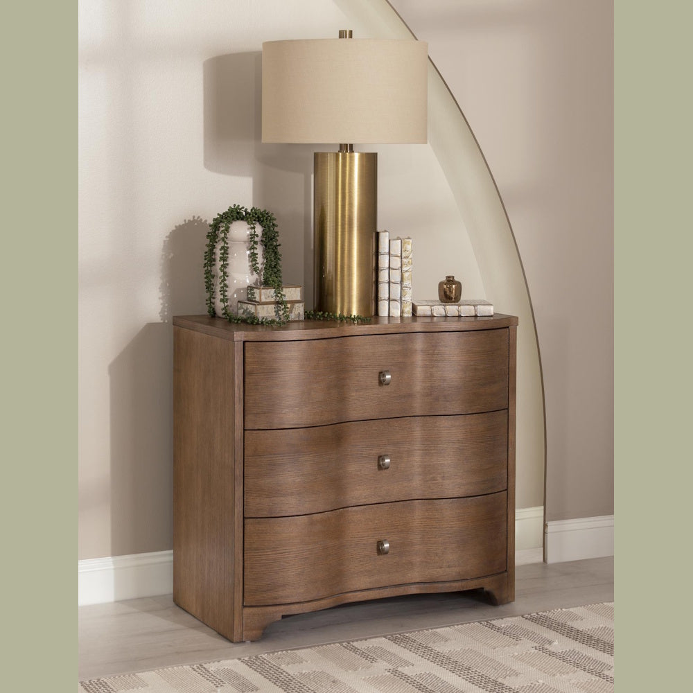 Modern wavy wood dresser with gold lamp and decor.