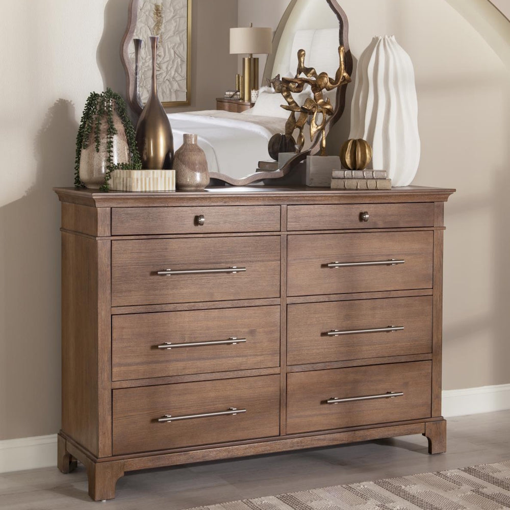 Wooden eight-drawer dresser with metal bar handles, styled with decor items and a mirror above.