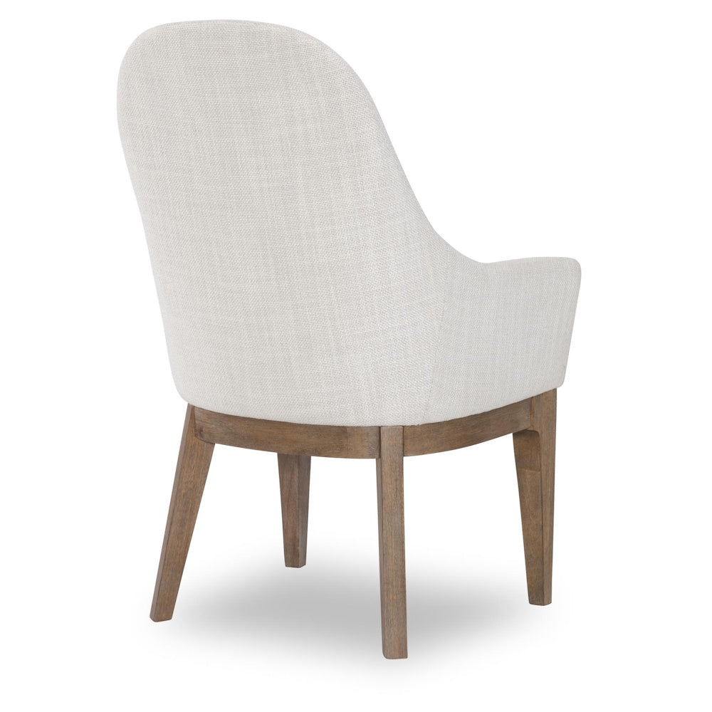 Back view of a modern cream upholstered dining chair with solid wood legs.