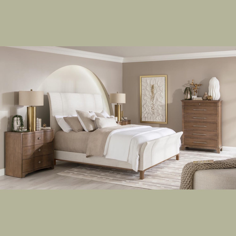 Modern upholstered bed set with wood dresser, nightstand, and gold lamps in a neutral bedroom.