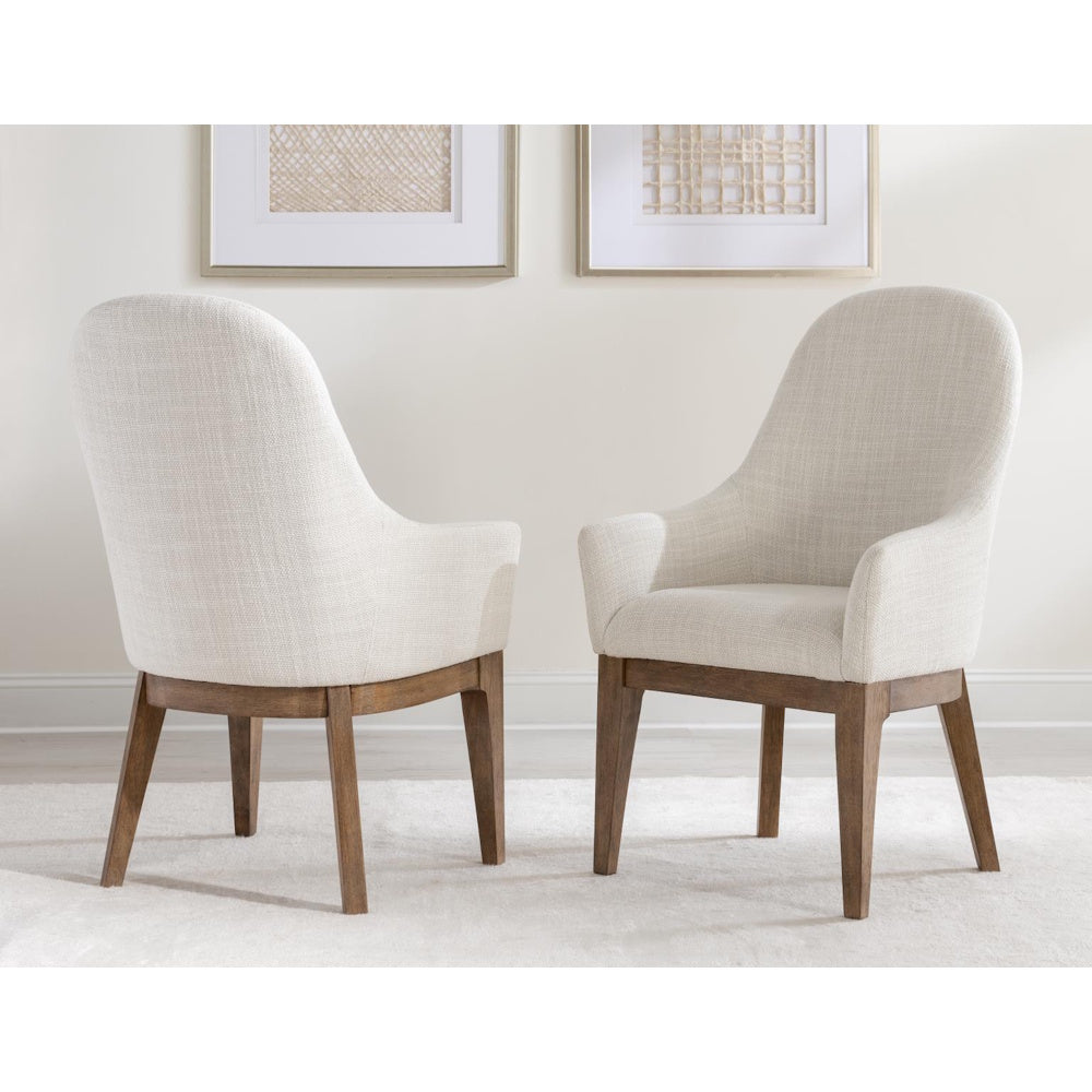 Pair of modern cream upholstered dining chairs with walnut wood legs on a white rug.