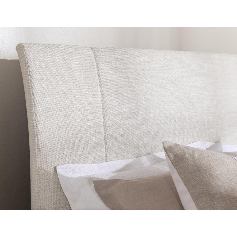 Modern cream upholstered headboard with textured linen fabric and neutral accent pillows.