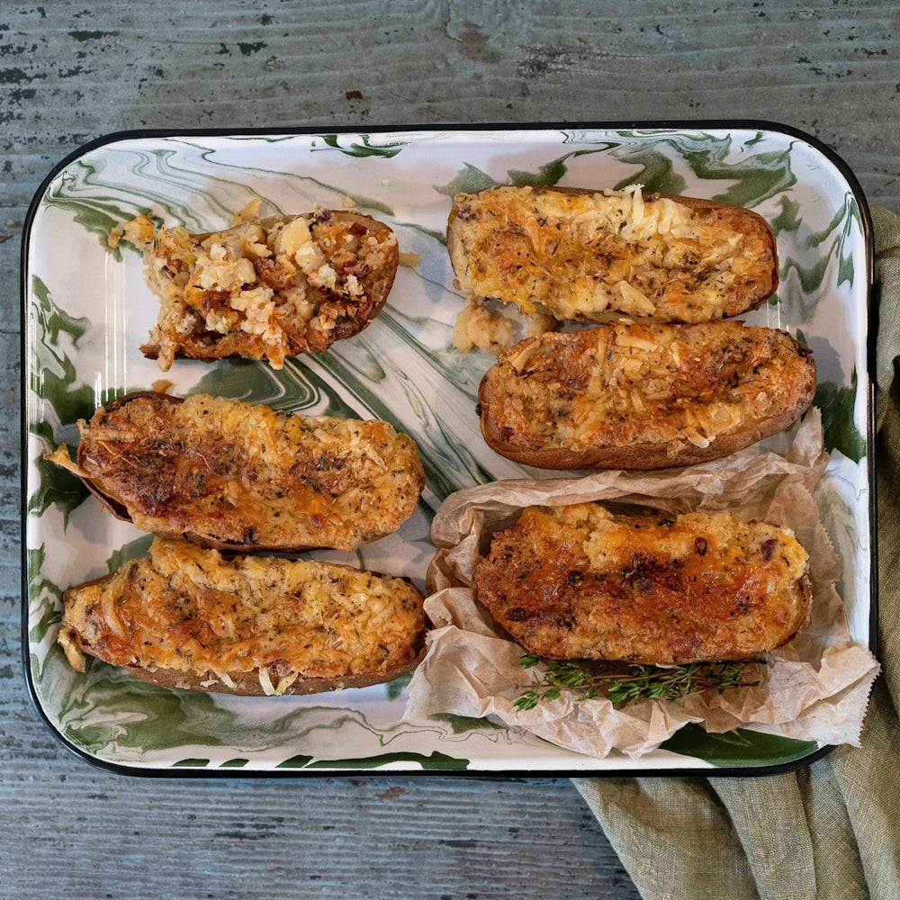 Twice-baked potato halves seasoned and baked to a golden brown, served on a green marbled tray.