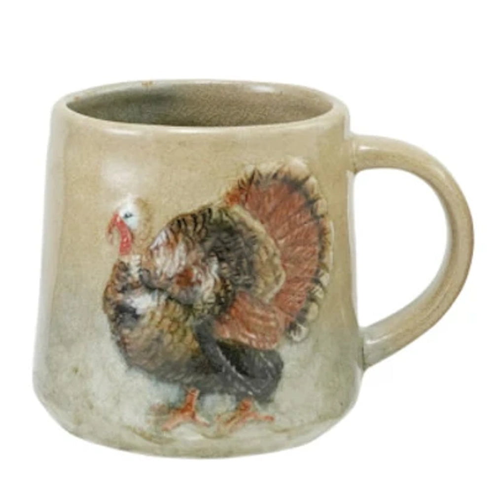 A rustic stoneware mug featuring a hand-painted, embossed turkey illustration on a neutral beige ceramic surface.